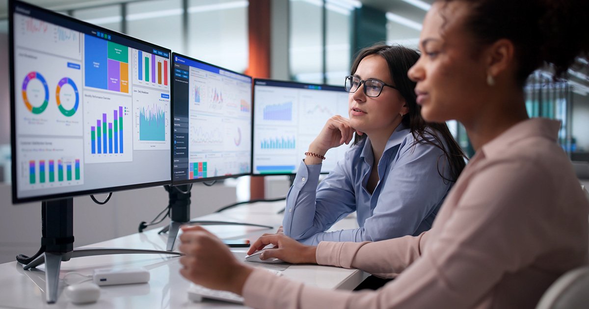 Two colleagues at a computer looking at a data dashboard Two colleagues at a computer looking at a data dashboard