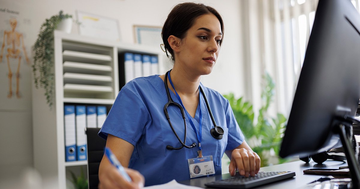 healthcare provider at desk working on computer with health records healthcare provider at desk working on computer with health records